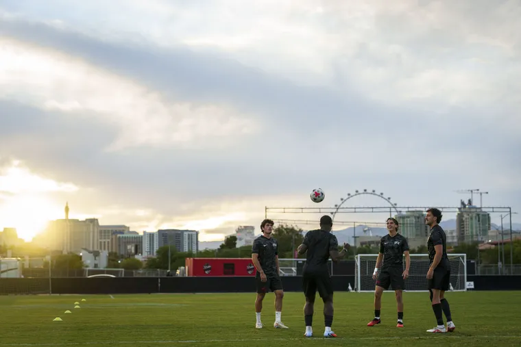Manuel juggling a ball with three UNLV teammates at sunset training, with the Las Vegas skyline and High Roller wheel behind